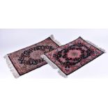 A near pair of small Iranian rugs with fringed ends, each with central black field designed with
