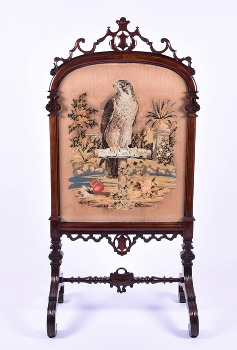 A large Victorian mahogany carved fire screen  surmounted by shield and scroll decoration, the
