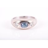 A diamond and sapphire ring centred with a rounded cabochon sapphire flanked with two round-cut