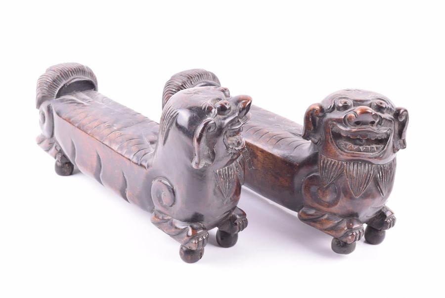 A pair of early Chinese hardwood foo dogs possibly used as scroll weights, the guardians heads sit