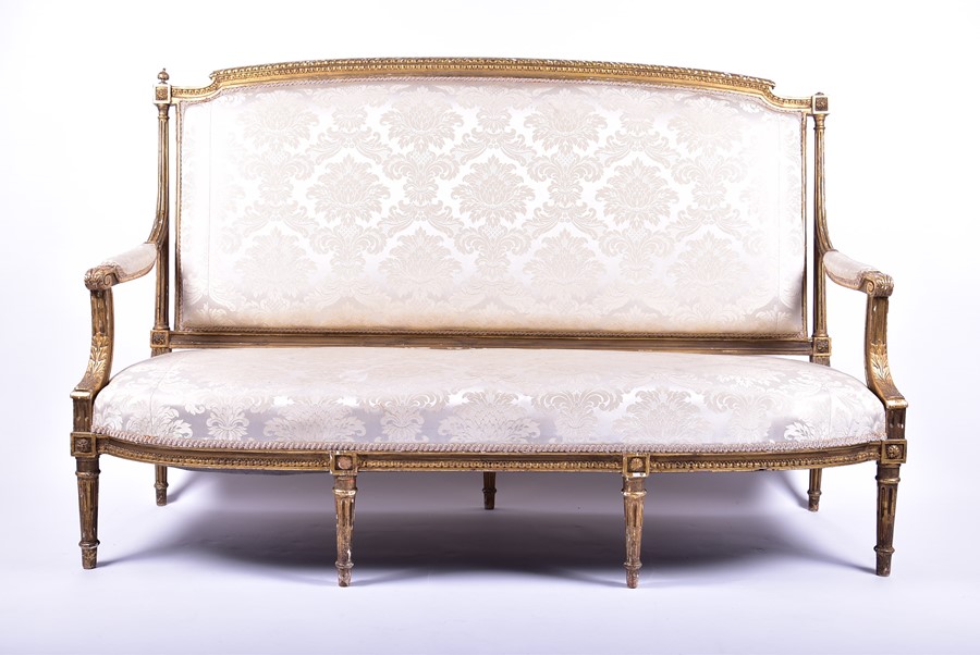 A Louis XVI style gilded sofa upholstered with light floral pattern fabric, the frame with gadroon