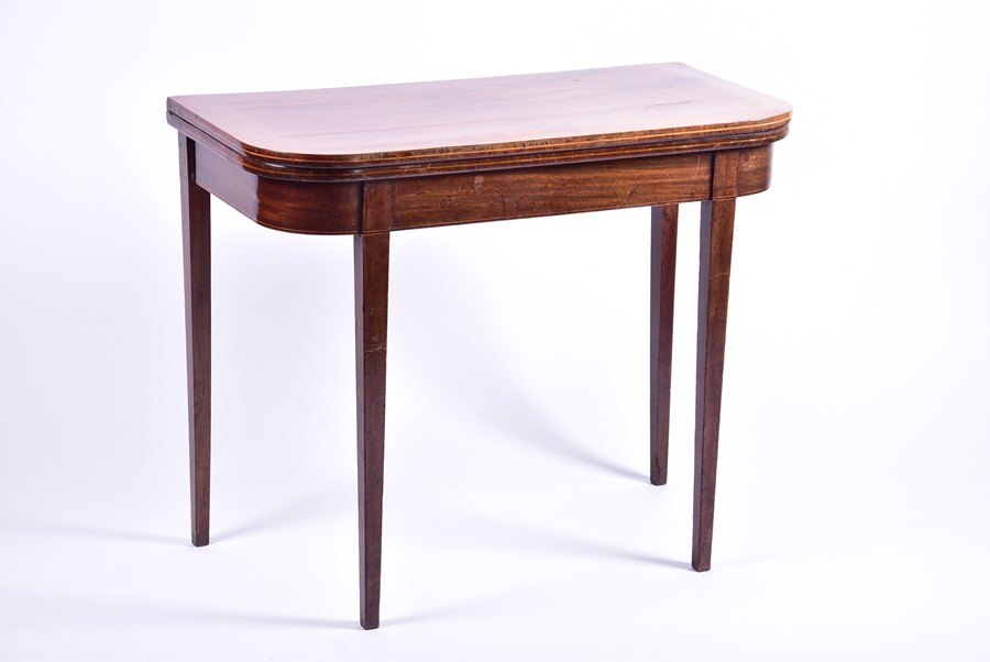 An Edwardian mahogany fold-over card table opening to reveal a green baize, on tapering legs, 90