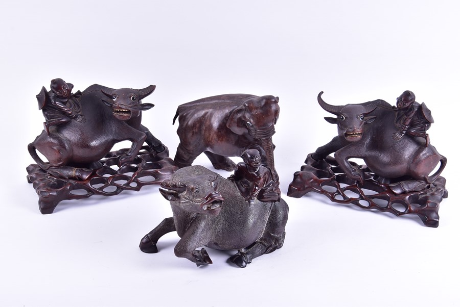 A pair of Chinese carved hardwood 'Buffalo and child' models with textured detail to the buffalos,