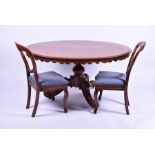 A Victorian walnut oval loo table and chairs the table with a shaped skirt around the edge,