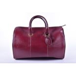 A Cartier Must De Logos 2c Bordeaux travelbag with yellow metal finishings and cartier monogram to