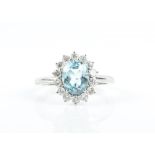An 18ct white gold, diamond, and aquamarine ring set with a mixed oval-cut aquamarine, surrounded