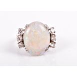 An opal and diamond ring set with an oval cabochon opal, flanked with six round brilliant-cut