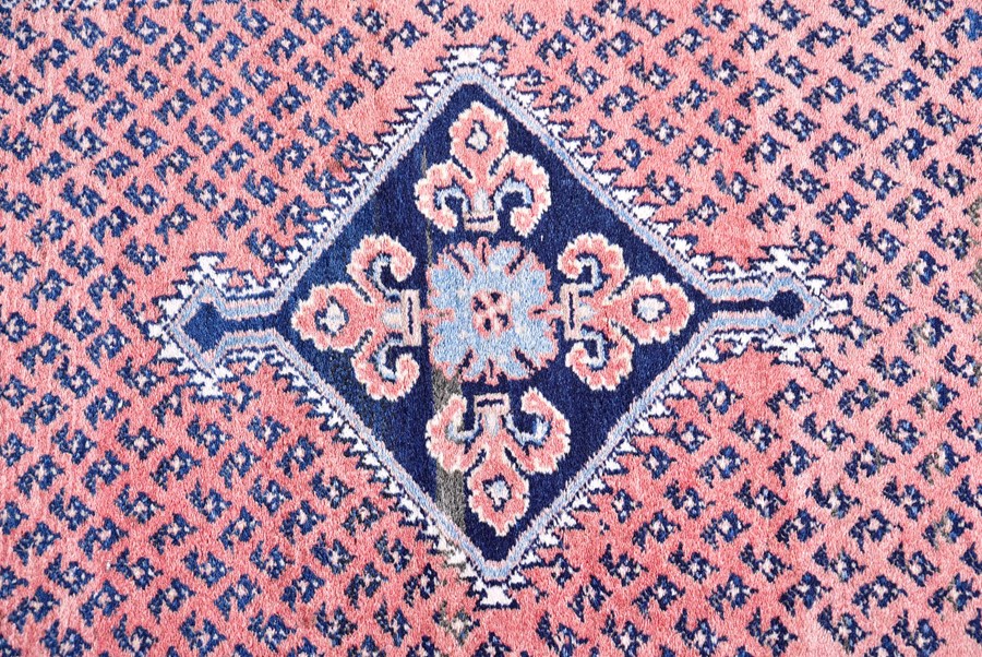 A Persian Qashqai carpet designed with central indigo diamond medallion against a salmon pink ground - Image 3 of 4