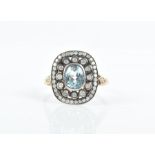 A yellow metal, diamond, and blue topaz ring centred with an oval-cut topaz, surrounded with