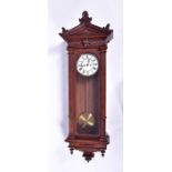 A 20th century oak-case Vienna wall clock with arched pediment over fluted columns, the enamel