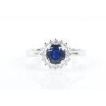 An 18ct white gold, diamond, and blue sapphire cluster ring set with a round-cut sapphire, 5.5 mm