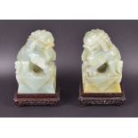 A pair of green jade foo dogs  mounted to bespoke carved hardwood stands, 18.5 cm total height.