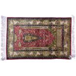 A highly detailed Eastern silk fringed rug the central blood red field interspersed with a central