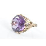 A yellow metal and Alexandrite style ring set with a round-cut synthetic corundum, with stylised