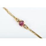A 9ct yellow gold, diamond, and ruby bracelet centred with a faceted oval-cut ruby, flanked with two