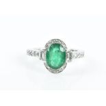 An 18ct white gold, diamond, and emerald cluster ring set with a mixed oval-cut emerald of