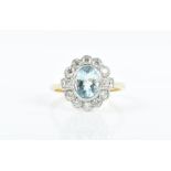 An 18ct yellow gold, diamond, and aquamarine cluster ring set with an oval-cut aquamarine within a