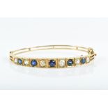 A yellow gold, diamond, and sapphire bangle set with alternated old-cut diamonds and vari-coloured