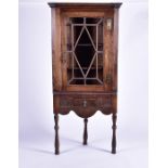 A Georgian oak corner display cabinet with moulded dentil pediment above a glazed door with