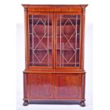 A reproduction 19th century style cupboard bookcase with rope twist columns flanking twin astral-