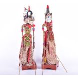 Two 20th century Indonesian carved and hand-painted puppets mounted on wooden stands, 66 cm high. (