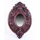 A carved Black Forest oval mirror designed with scrolled leaves, fruit and small pine cones, the