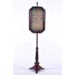 A Victorian walnut pole screen with embroidered sampler panel (dated 1848) behind glass, on an