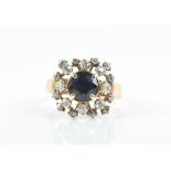 An unusual 14ct yellow gold, diamond, and sapphire ring centred with a round-cut dark blue sapphire,
