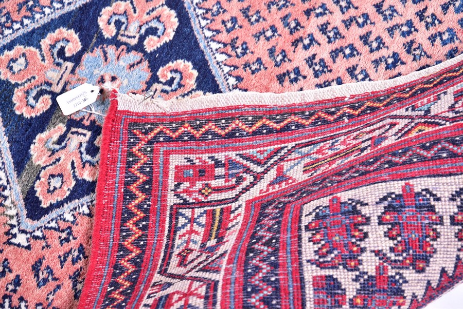 A Persian Qashqai carpet designed with central indigo diamond medallion against a salmon pink ground - Image 2 of 4