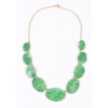 A Chinese yellow metal and jade necklace comprised of nine graduated plaques with pierced and