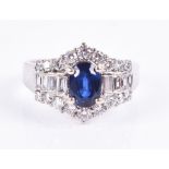 An 18ct white gold, diamond, and sapphire ring set with a mixed oval-cut blue sapphire, flanked with