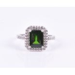 A 14ct white gold, diamond, and green gemstone ring set with an emerald-cut green stone (possibly