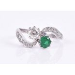 An 18ct white gold, diamond, and emerald crossover ring set with a round-cut emerald and a round-cut
