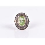 A silver gilt, diamond, and green gemstone ring set with a mixed oval-cut gem (possibly peridot),