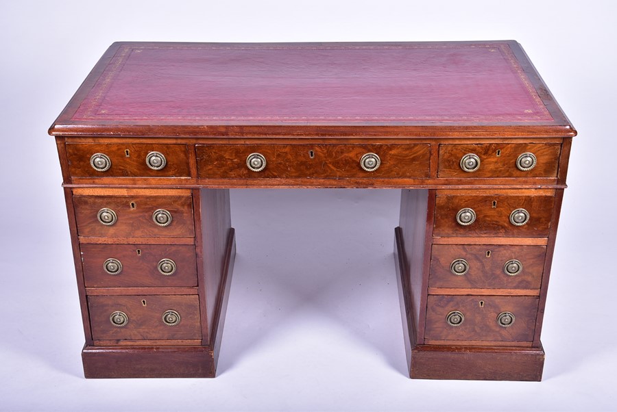 A Victorian figured walnut small pedestal desk the inset red leather top over three frieze drawers