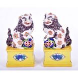 A pair of 20th century Chinese porcelain dogs of fo on stands their paws resting upon orbs,