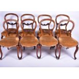 A set of eight Victorian walnut balloon back dining chairs with carved foliate stretchers,