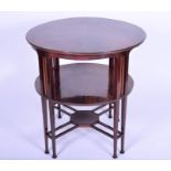 An Edwardian circular two-tier mahogany occasional table designed in the Arts and Crafts manner,