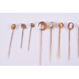 A collection of fourteen yellow metal stick pins various designs, to include two terminating with