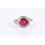 A 9ct yellow gold, diamond, and ruby ring the crossover mount set with a mixed oval-cut ruby, size