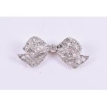 A millegrain set diamond bow brooch centred with an old-cut diamond weighing approximately 0.08