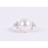 An 18ct white gold, diamond, and pearl ring set with a large white pearl, set to the shoulders