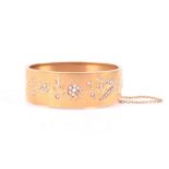 A late 19th century French 18 carat yellow gold and diamond bangle with engraved decoration set with