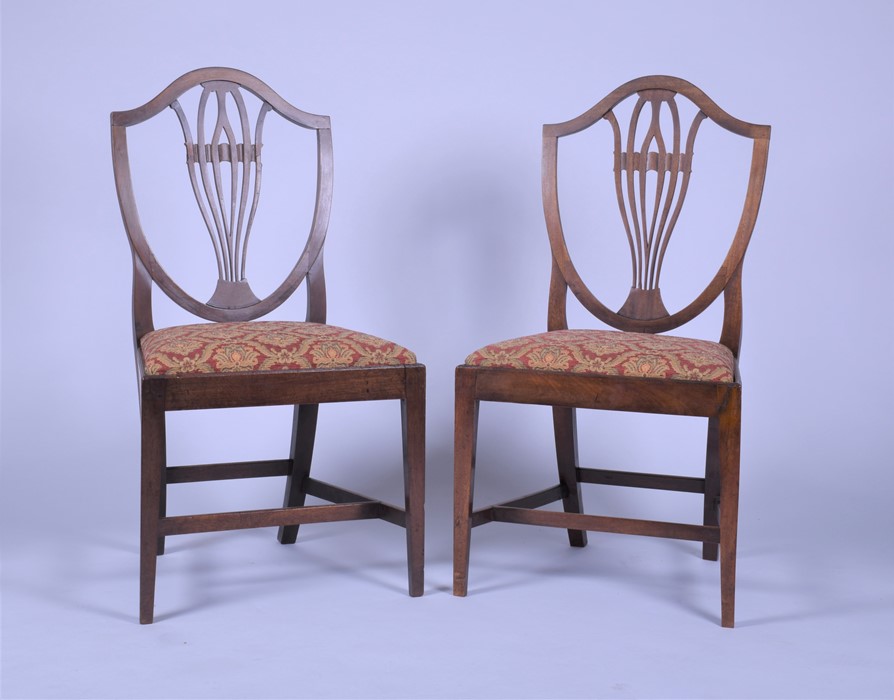 A pair of late Georgian mahogany shield back dining chairs after a design by George Hepplewhite with