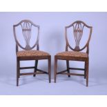 A pair of late Georgian mahogany shield back dining chairs after a design by George Hepplewhite with