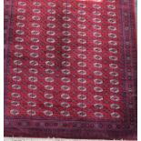 A large Persian Bokhara style rug decorated with ornate border, geometric motifs and medallions on a
