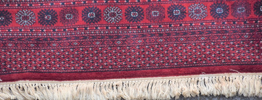 A large Persian Bokhara style rug decorated with ornate border, geometric motifs and medallions on a - Image 5 of 5