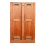 A mid 20th century two-door oak cupboard with part internal shelving and metal grills on one side