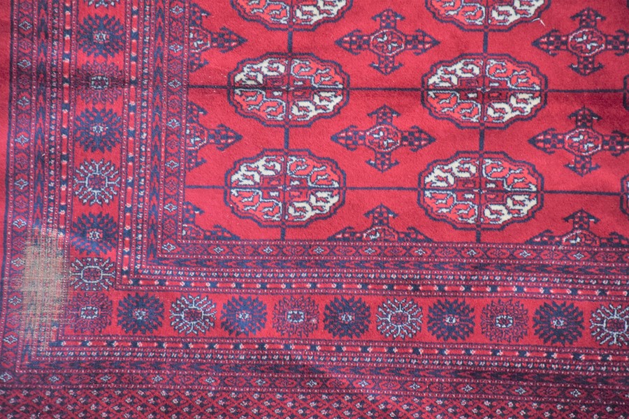 A large Persian Bokhara style rug decorated with ornate border, geometric motifs and medallions on a - Image 4 of 5