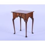 A George II walnut lowboy with a central drawer flanked by two narrow drawers, on tapering legs